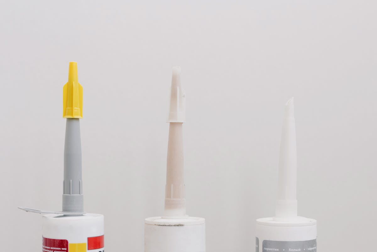 A set of plastic tubes of sealants and adhesives in a workshop.