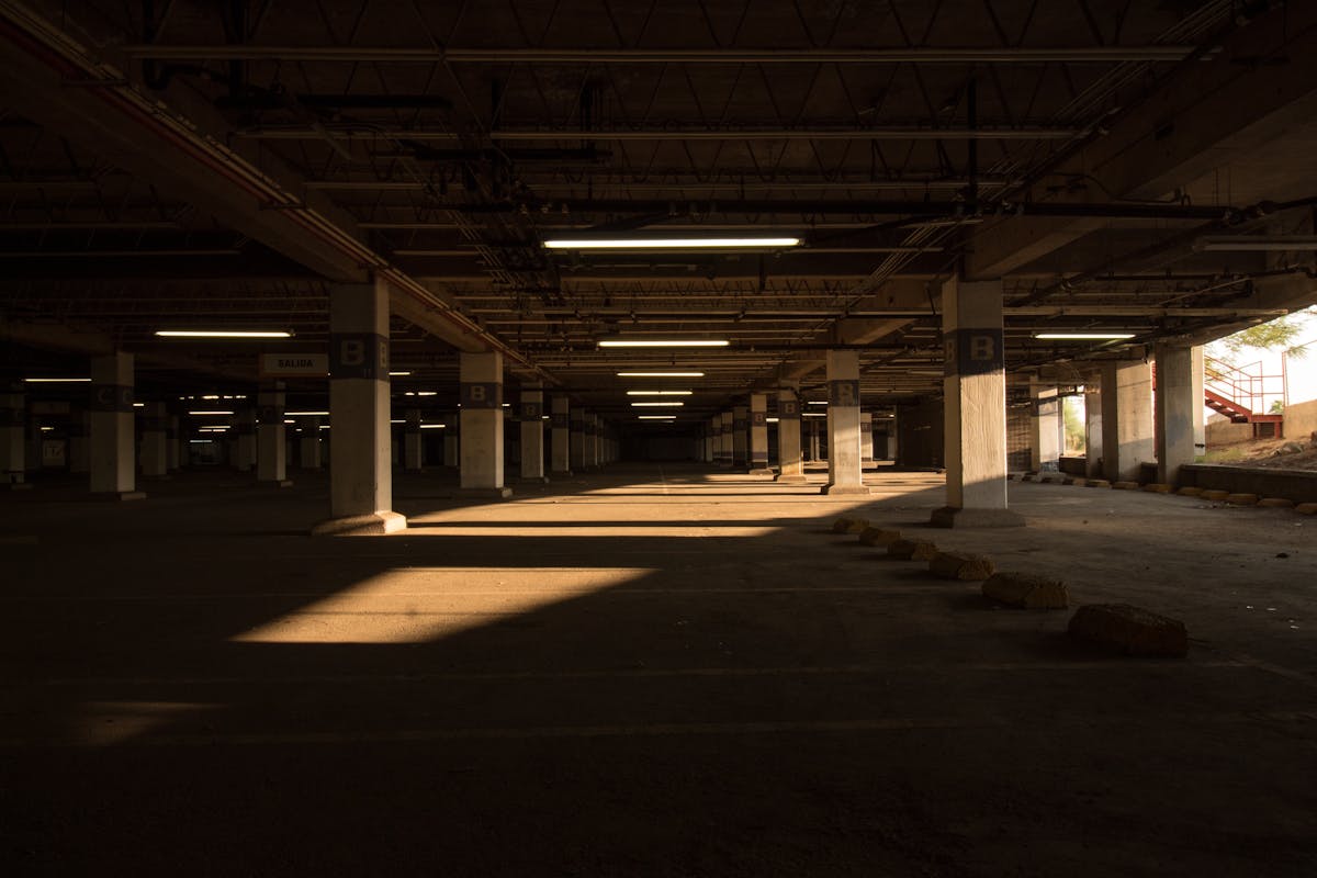 Sunlight cutting across an empty parking lot at midday.