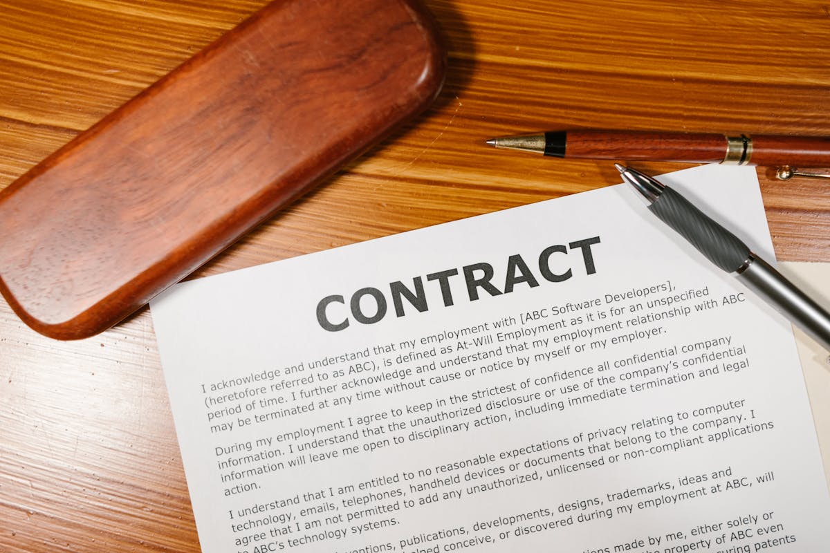 A loan contract laid out on a wooden desk with a pen.