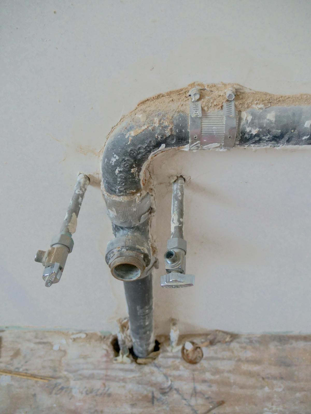 Exposed plumbing pipes with rustic textures running along a wall.
